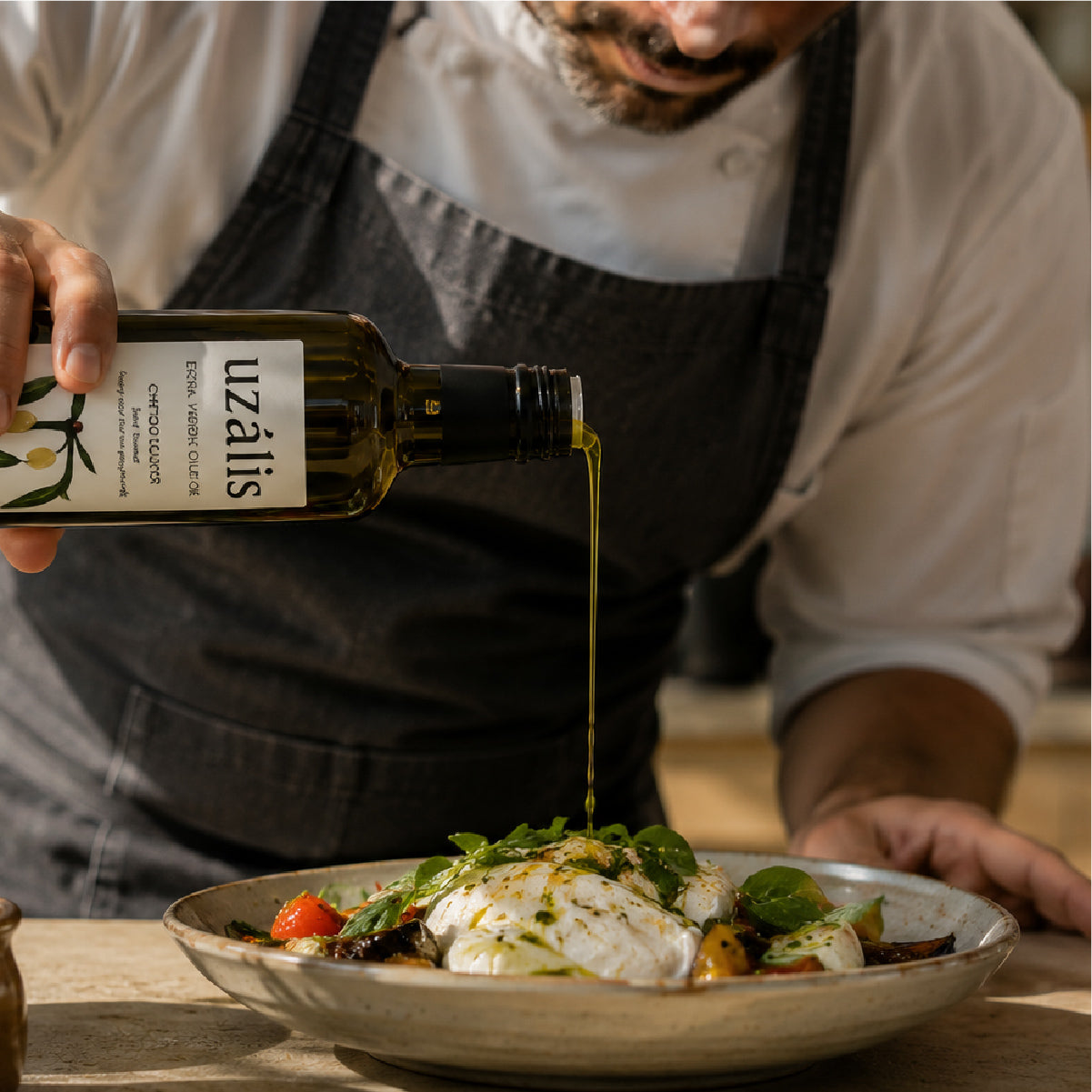 Chef finishing a Mediterranean dish with premium Tunisian extra virgin olive oil